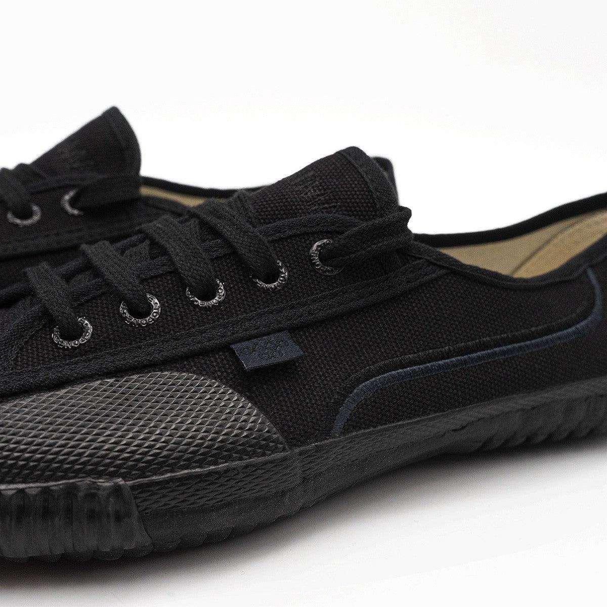 Détail des œillets, du lacet et du liseré bleu marine des chaussures Shaolin FUJIMAE tout noir