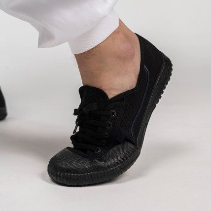 Chaussures Shaolin FUJIMAE tout noir portées aux pieds avec un pantalon blanc