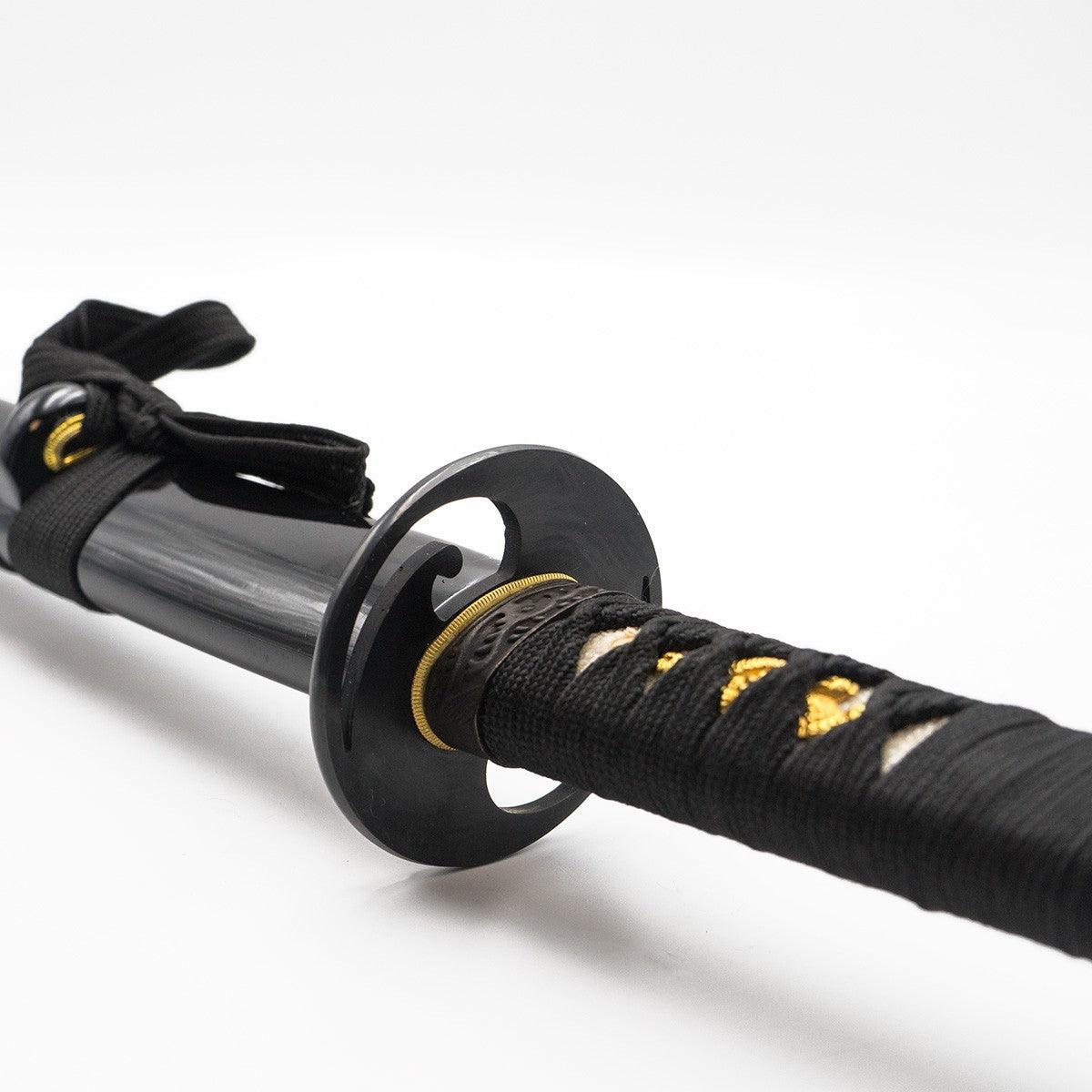 Close-up of black lacquered saya and intricately wrapped tsuka with black and gold details of Katana en Acier Damas for martial arts practice