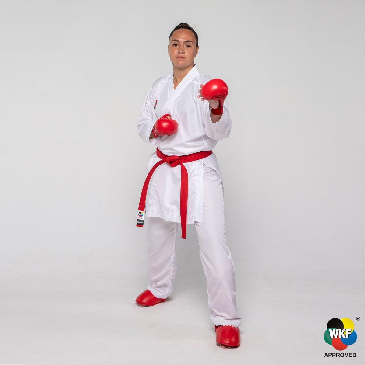 Professional karateka wearing WKF-approved lightweight white Kumite ProWear Hyperlite karate gi with red belt and gloves, designed for comfort and performance in competition