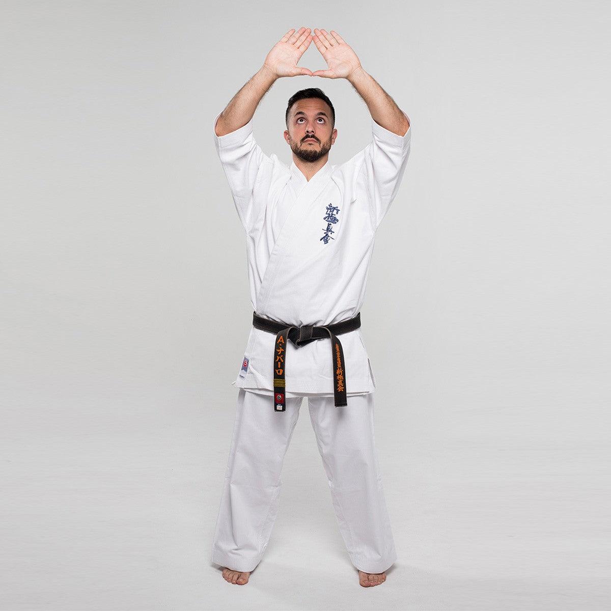 Man practicing karate in a white Shinkyokushin Yantsu Karate Gi with black belt, demonstrating a kata pose