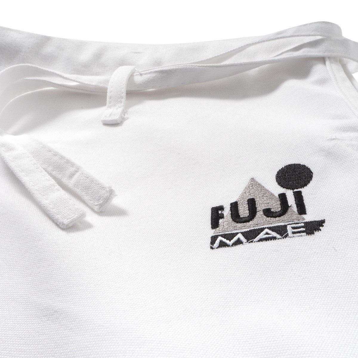 Close-up of white FUJIMAE Pantalon Karaté Legacy II karate pants with embroidered logo and drawstring waistband