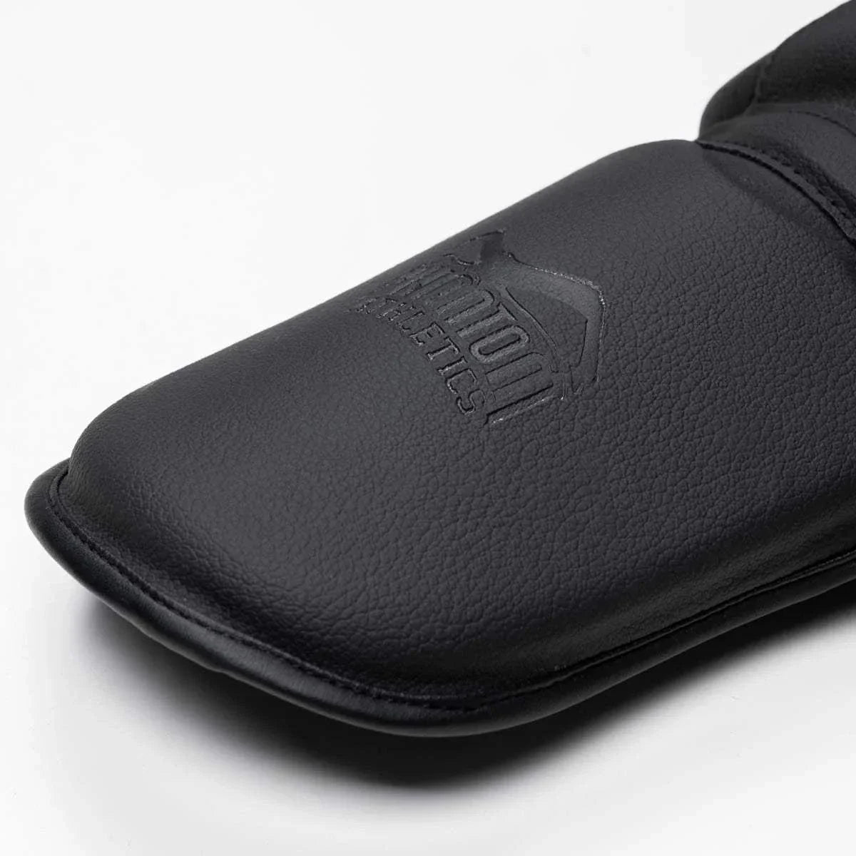 Protège-Tibias Phantom MT-Pro noir en cuir synthétique, protection complète pour Muay Thaï et kickboxing, légers et résistants avec attaches velcro.