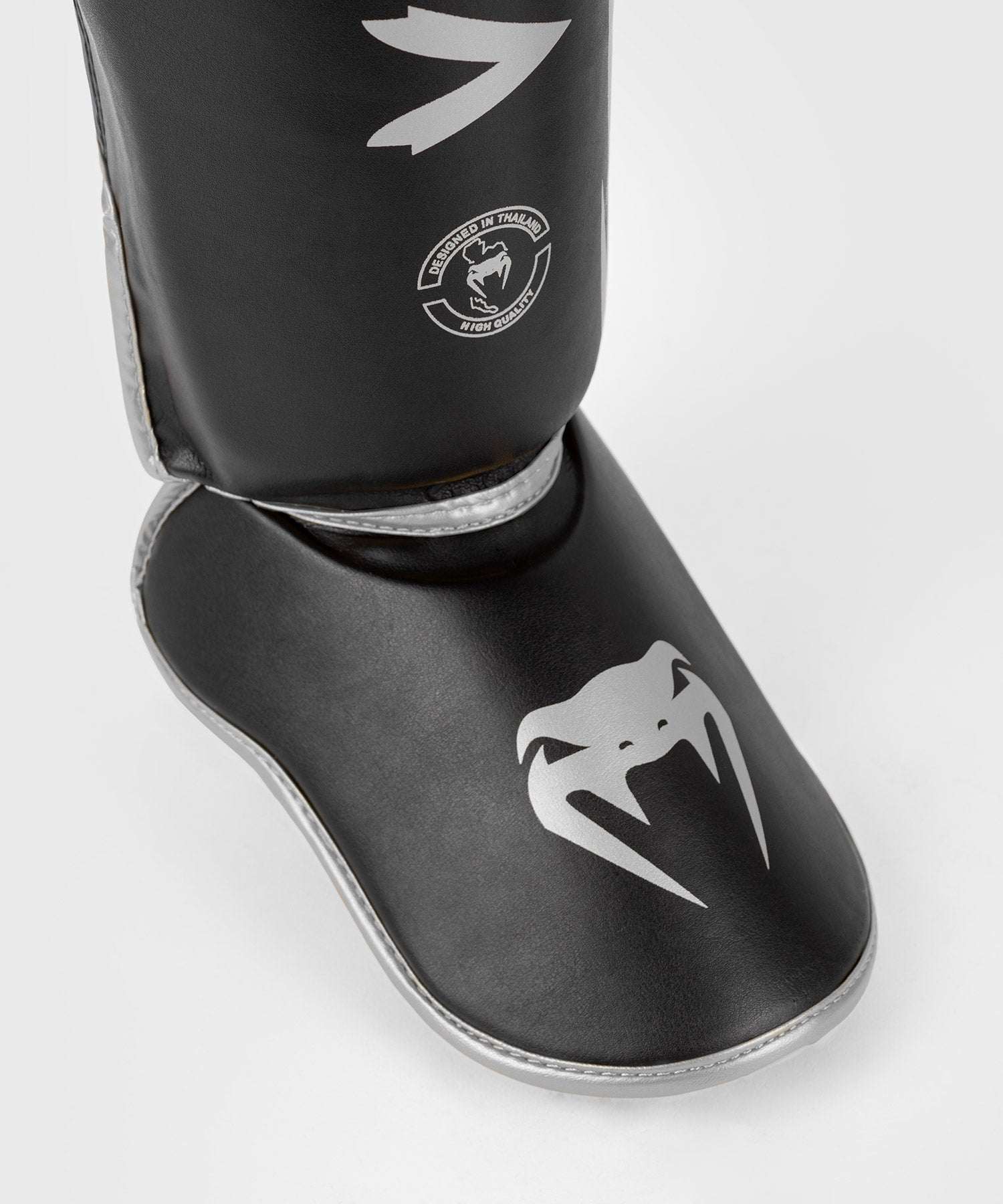 Protège-tibias Venum Challenger noir et argent pour Muay Thaï et MMA avec mousse haute densité et double velcro.
