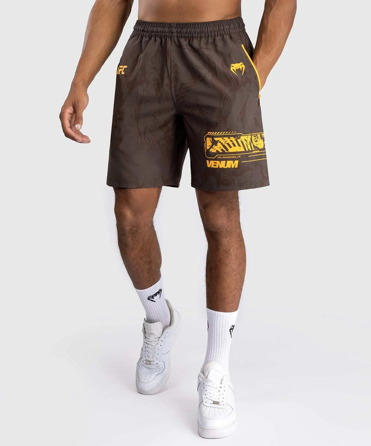 Men wearing UFC Fusion par Venum brown performance shorts with yellow accents and elastic waistband for athletic training