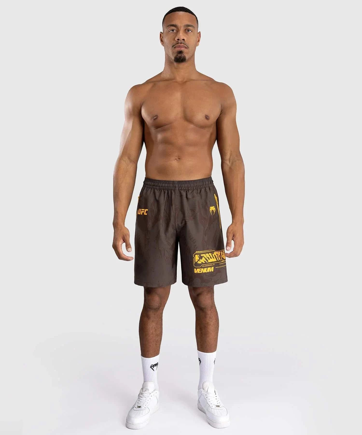 Athlete wearing UFC Fusion par Venum black performance shorts with yellow logo and elastic waistband.