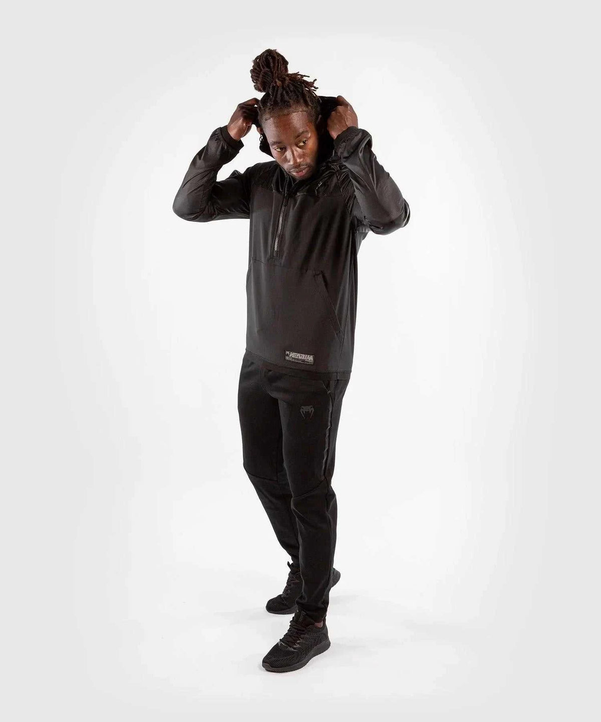man wearing black Venum Laser XT hoodie sweatshirt and matching black jogging pants adjusting hood