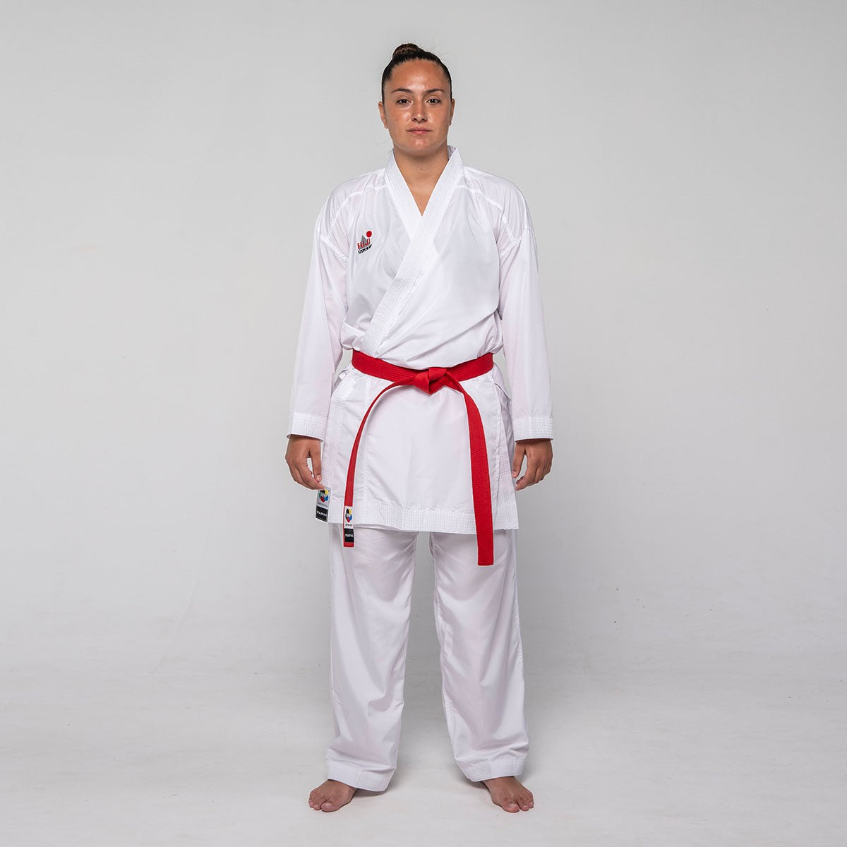 Professional karateka wearing white Kumite ProWear Hyperlite karate gi with red belt and breathable 100% polyester fabric designed for competition.