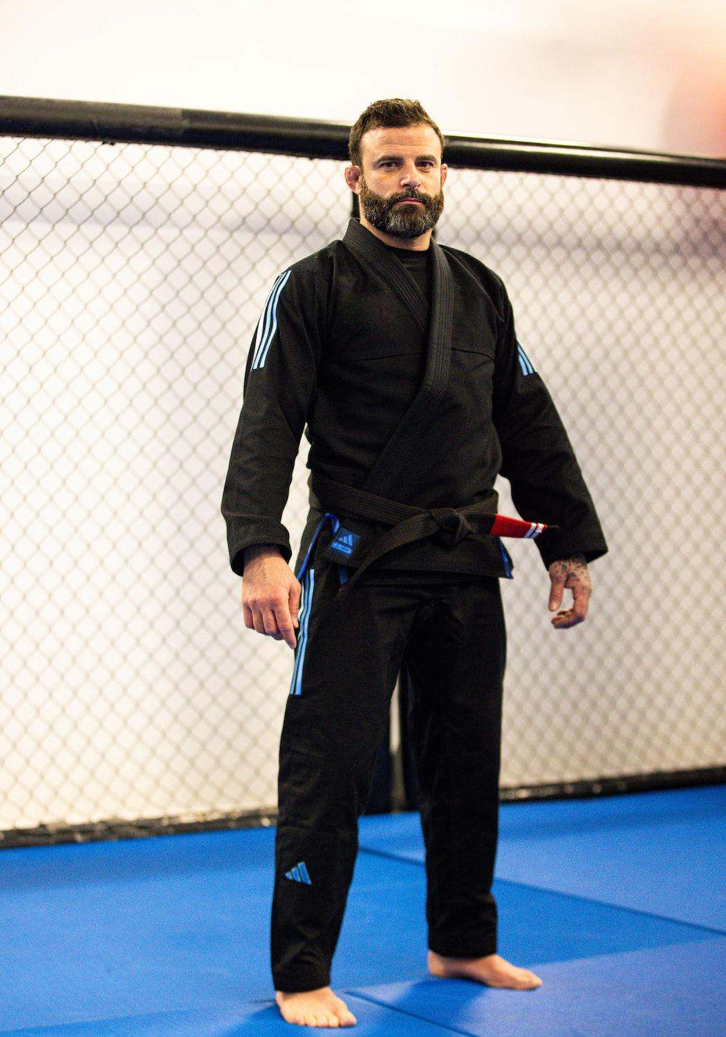 Kimono de JJB Adidas Contest 2.0 noir avec bandes bleu dégradé, conçu en matériaux résistants et confortables pour le jiu-jitsu.