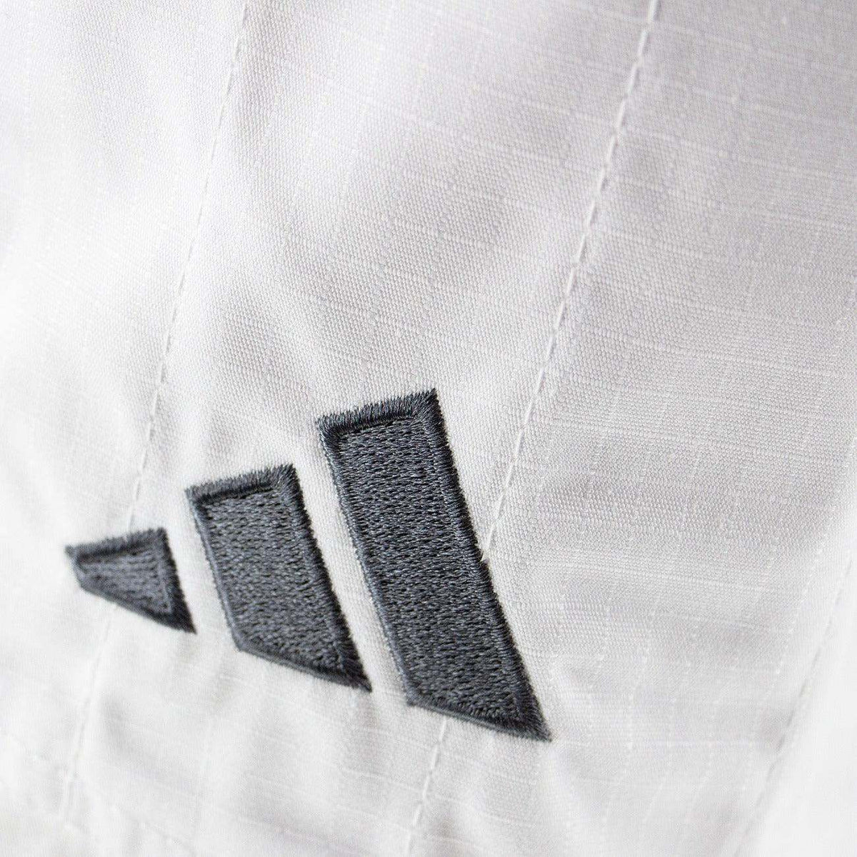Kimono de JJB Adidas Contest 2.0 blanc en ripstop avec logo brodé gris, résistant et léger pour jiu-jitsu.
