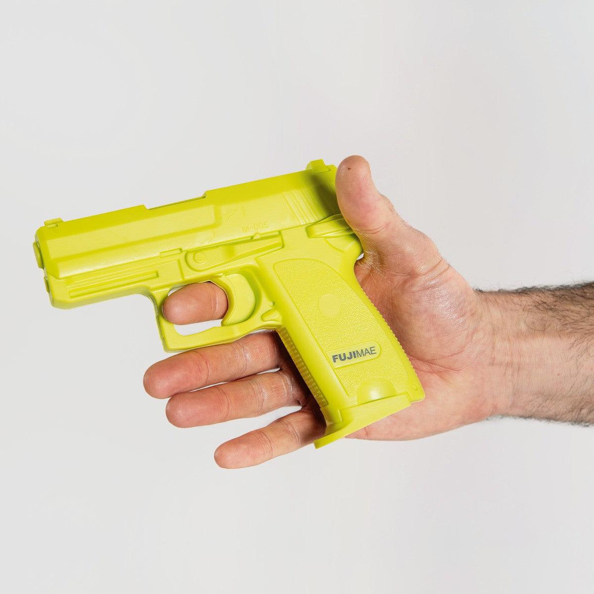 Yellow FUJIMAE SD-H93C training pistol made of thermoplastic rubber held in hand for realistic self-defense practice
