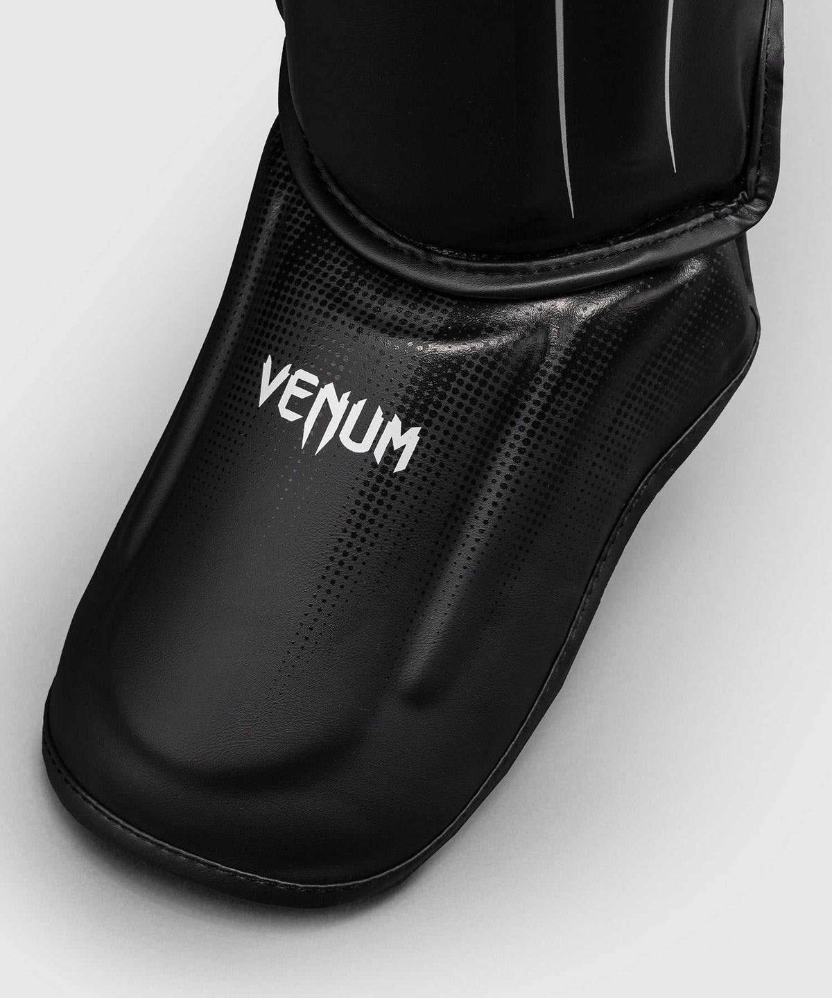 Protège-tibias Venum Stealth noir et blanc pour kickboxing, Muay Thaï et MMA avec mousse multi-densité et fermetures triple point.