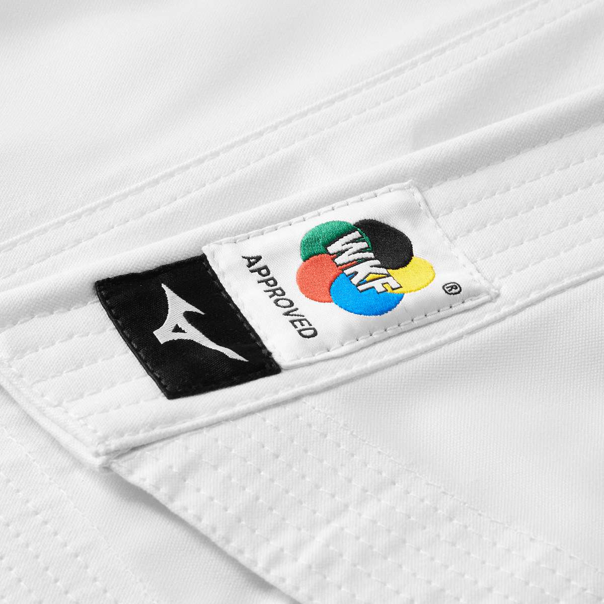 Close-up of white Mizuno karate kimono jacket with WKF approval patch and Mizuno logo on durable cotton fabric